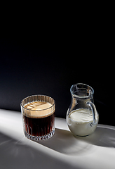 Image showing coffee in glass and jug of milk or cream on table