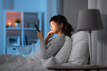 Image showing asian woman with smartphone in bed at night