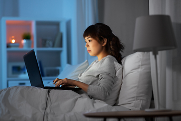Image showing woman with laptop in bed at home at night