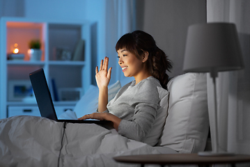 Image showing woman having video call on laptop in bed at night