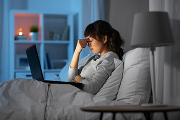 Image showing stressed woman with laptop working in bed at night