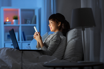 Image showing asian woman with smartphone in bed at night