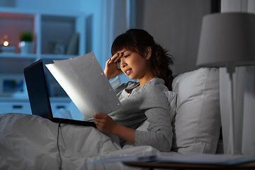 Image showing stressed woman with papers working in bed at night