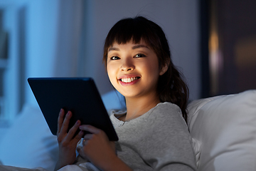 Image showing asian woman with tablet pc in bed at home at night