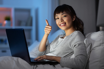 Image showing woman with laptop in bed at night shows thumbs up