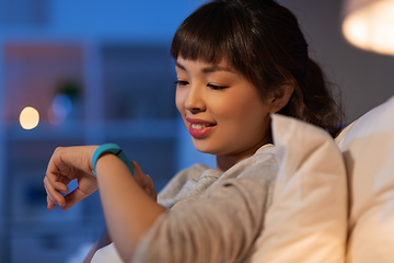 Image showing asian woman with health tracker in bed at night