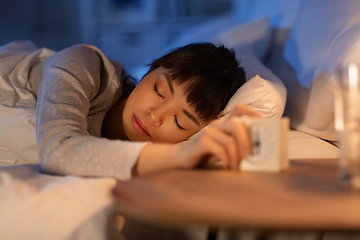 Image showing asian woman with clock sleeping in bed at night