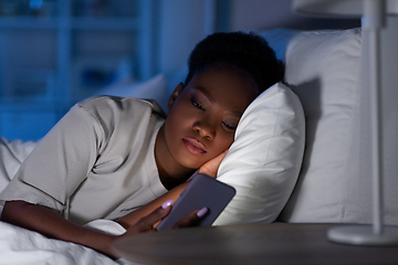Image showing african woman with smartphone in bed at night