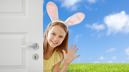 Image showing happy girl with easter bunny ears peeking out door