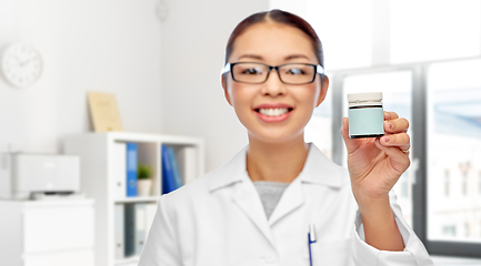 Image showing smiling female doctor holding jar of medicine