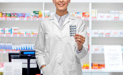 Image showing smiling female doctor holding medicine at pharmacy