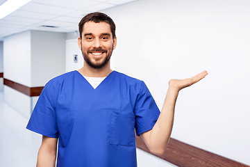 Image showing smiling male doctor holding something on hand