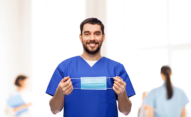 Image showing smiling male doctor in blue uniform with mask