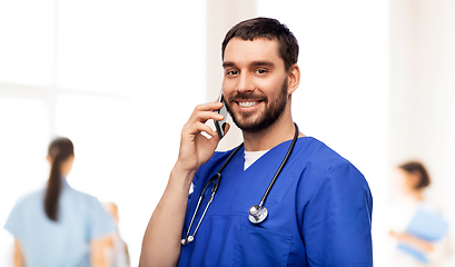 Image showing smiling doctor or male nurse calling on smartphone