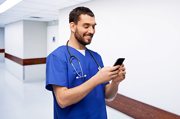 Image showing smiling doctor or male nurse using smartphone