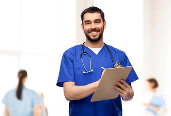 Image showing male doctor writing medical report on clipboard