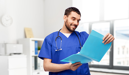 Image showing happy male doctor reading medical report in folder