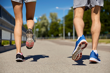 Image showing feet of sporty couple running along city road