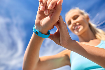 Image showing smiling young woman with fitness tracker outdoors