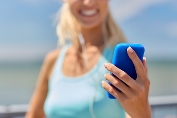 Image showing sporty young woman with smartphone and earphones