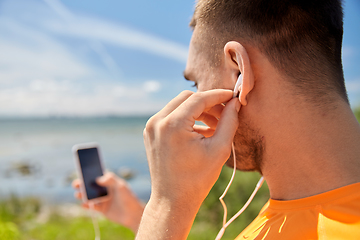 Image showing young man with smartphone and earphones outdoors