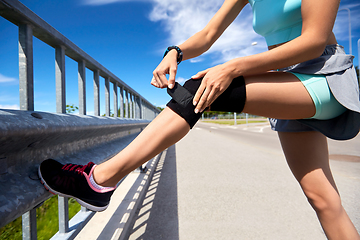 Image showing young woman in knee band doing sports outdoors