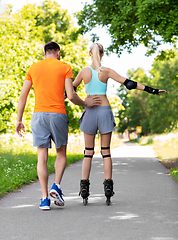 Image showing happy couple with roller skates riding outdoors