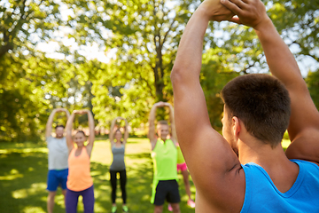 Image showing happy people exercising with trainer at park