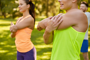 Image showing happy people exercising with trainer at park