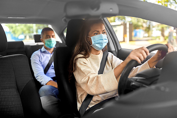 Image showing female driver in mask driving car with passenger