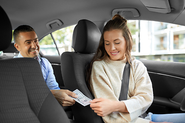 Image showing female car driver taking money from passenger