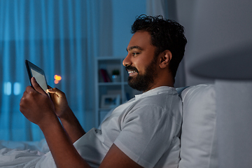 Image showing indian man with tablet pc in bed at home at night