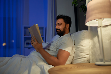 Image showing indian man reading book in bed at night