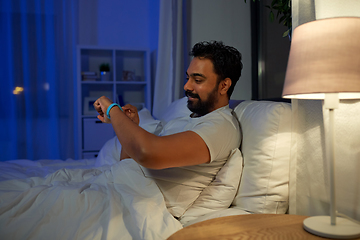 Image showing indian man with health tracker in bed at night