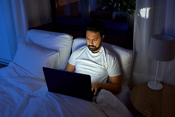 Image showing indian man with laptop in bed at home at night