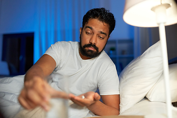 Image showing indian man with medicine and water in bed at night