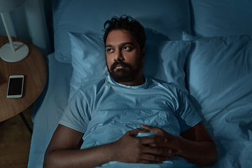 Image showing speelpess indian man lying in bed at night
