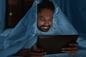 Image showing indian man with tablet pc in bed at home at night