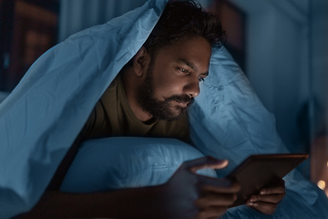 Image showing indian man with tablet pc in bed at home at night