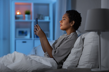 Image showing african woman with smartphone in bed at night