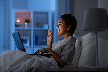 Image showing woman having video call on laptop in bed at night