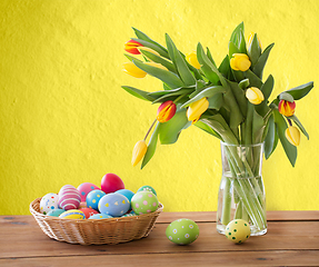 Image showing colored easter eggs in basket and flowers on table