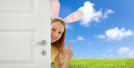 Image showing happy girl with easter bunny ears peeking out door