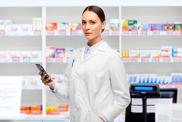 Image showing female doctor with smartphone at pharmacy