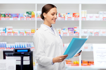 Image showing smiling female doctor with folder at pharmacy