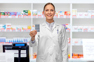 Image showing smiling female doctor holding medicine at pharmacy