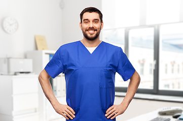 Image showing happy smiling doctor or male nurse in blue uniform