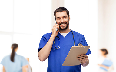 Image showing smiling doctor or male nurse calling on smartphone