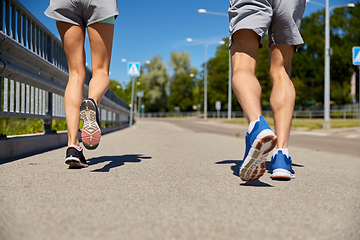 Image showing feet of sporty couple running along city road