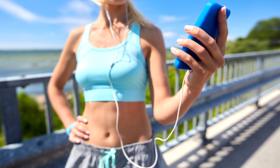 Image showing sporty young woman with smartphone and earphones